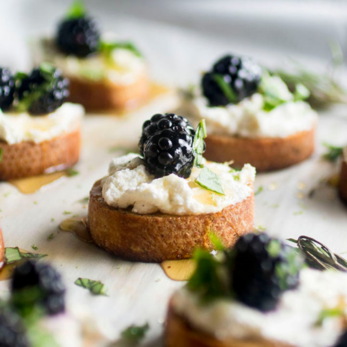 Tray of crostini topped with goat cheese and fresh blackberries.