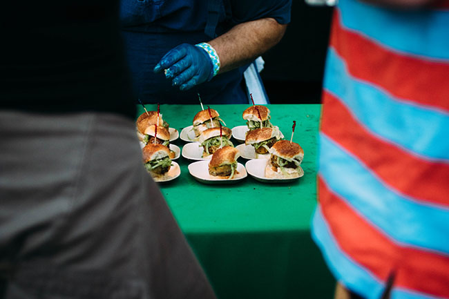 Plates of sliders on a green table.