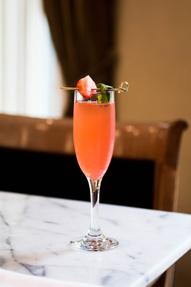 Strawberry mimosa in a champagne glass on a marble table.