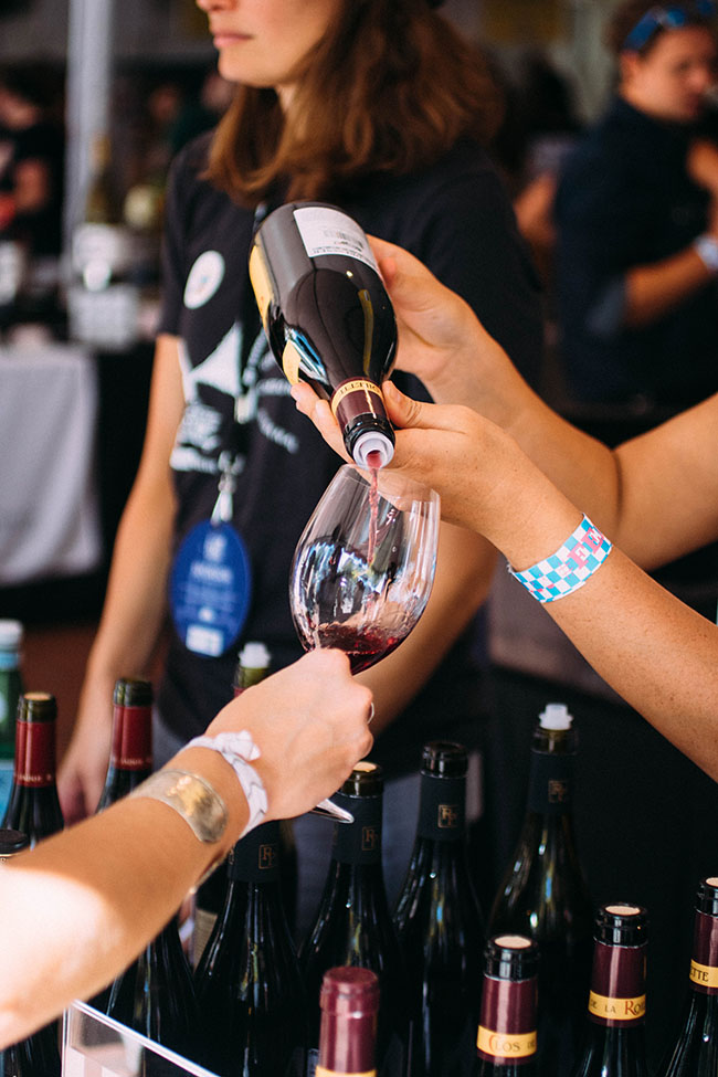 Pouring red wine into a tall wine glass.