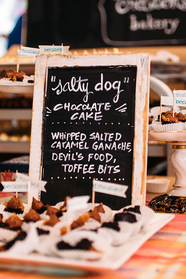 A chalkboard menu on a table full of desserts.