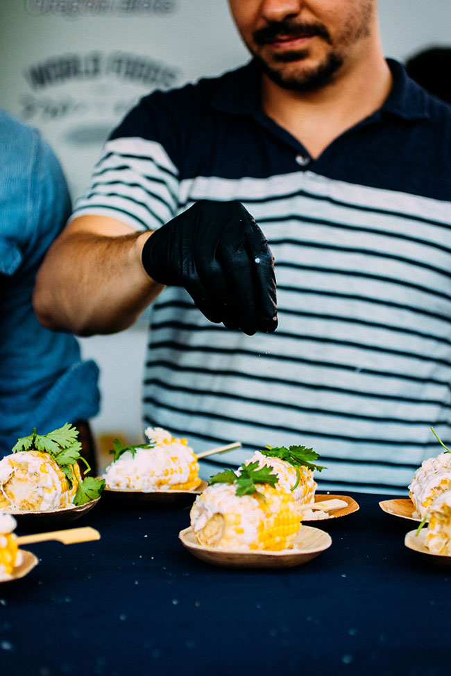 A chef sprinkles finishing salt over corn on the cob.