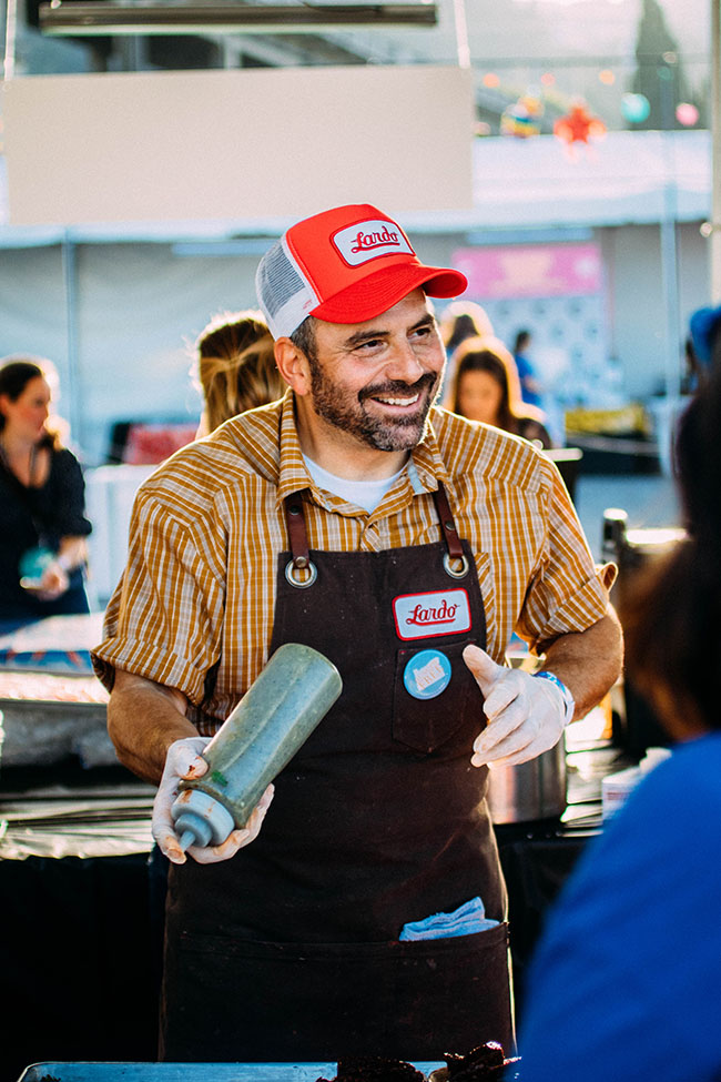A chef chats with an attendee while he plates his dish.
