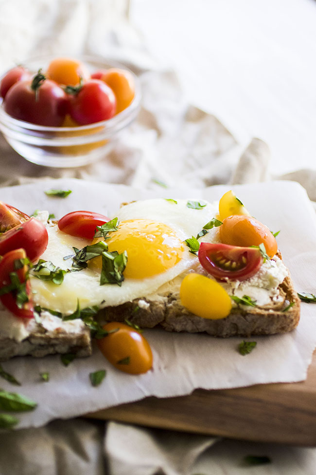 Toast topped with goat cheese, tomatoes, and a fried egg.