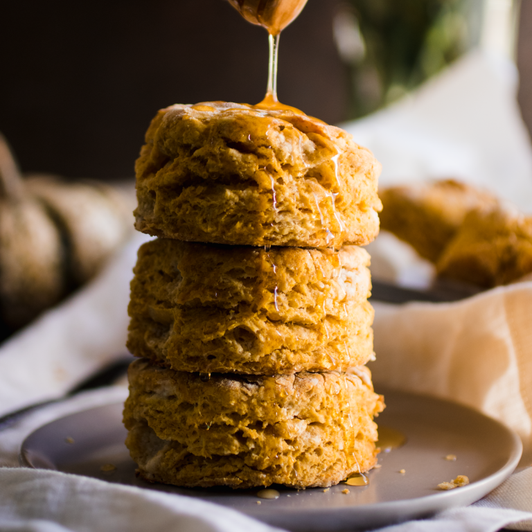Drizzling honey over a stack of pumpkin biscuits.