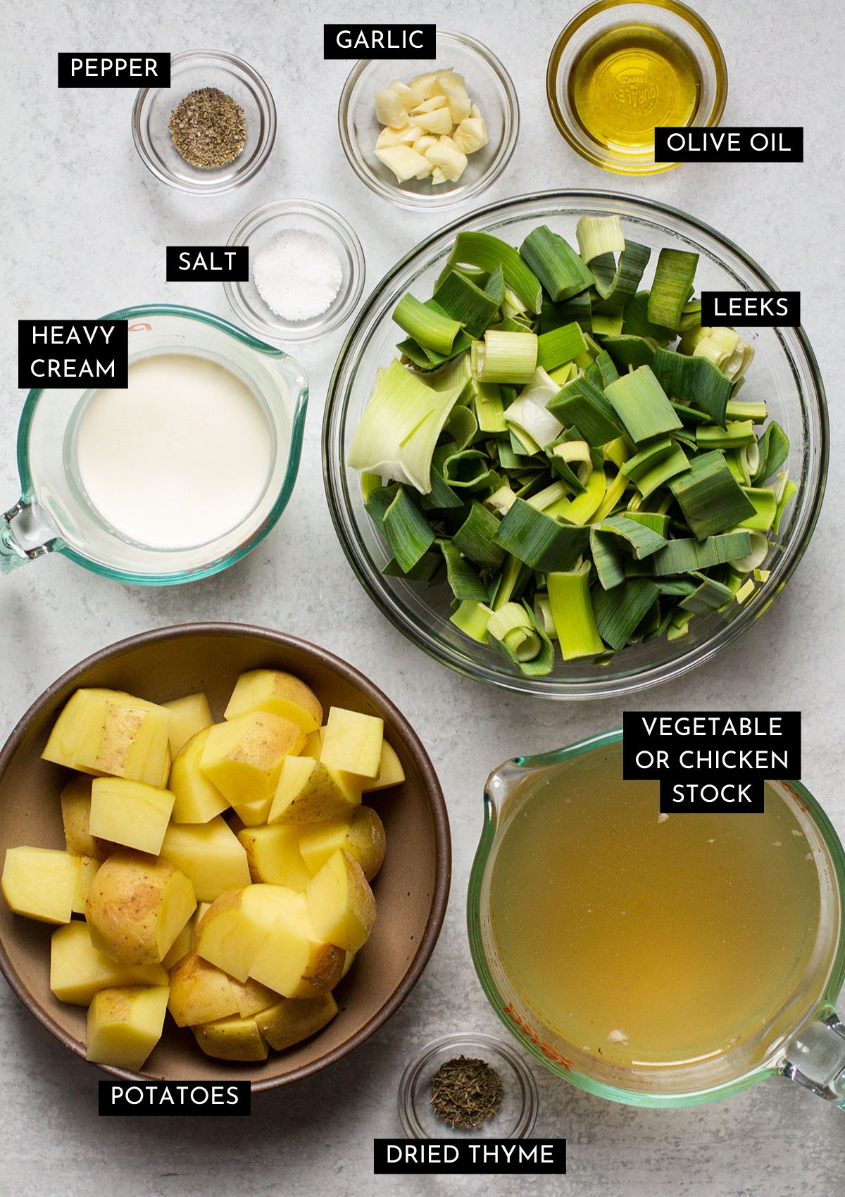 Soup ingredients, organized into individual glass bowls on a white table.