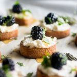Blackberry crostini on a baking sheet lined with white parchment paper.