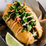 Sandwich topped with fresh cilantro and drizzled spicy mayo.