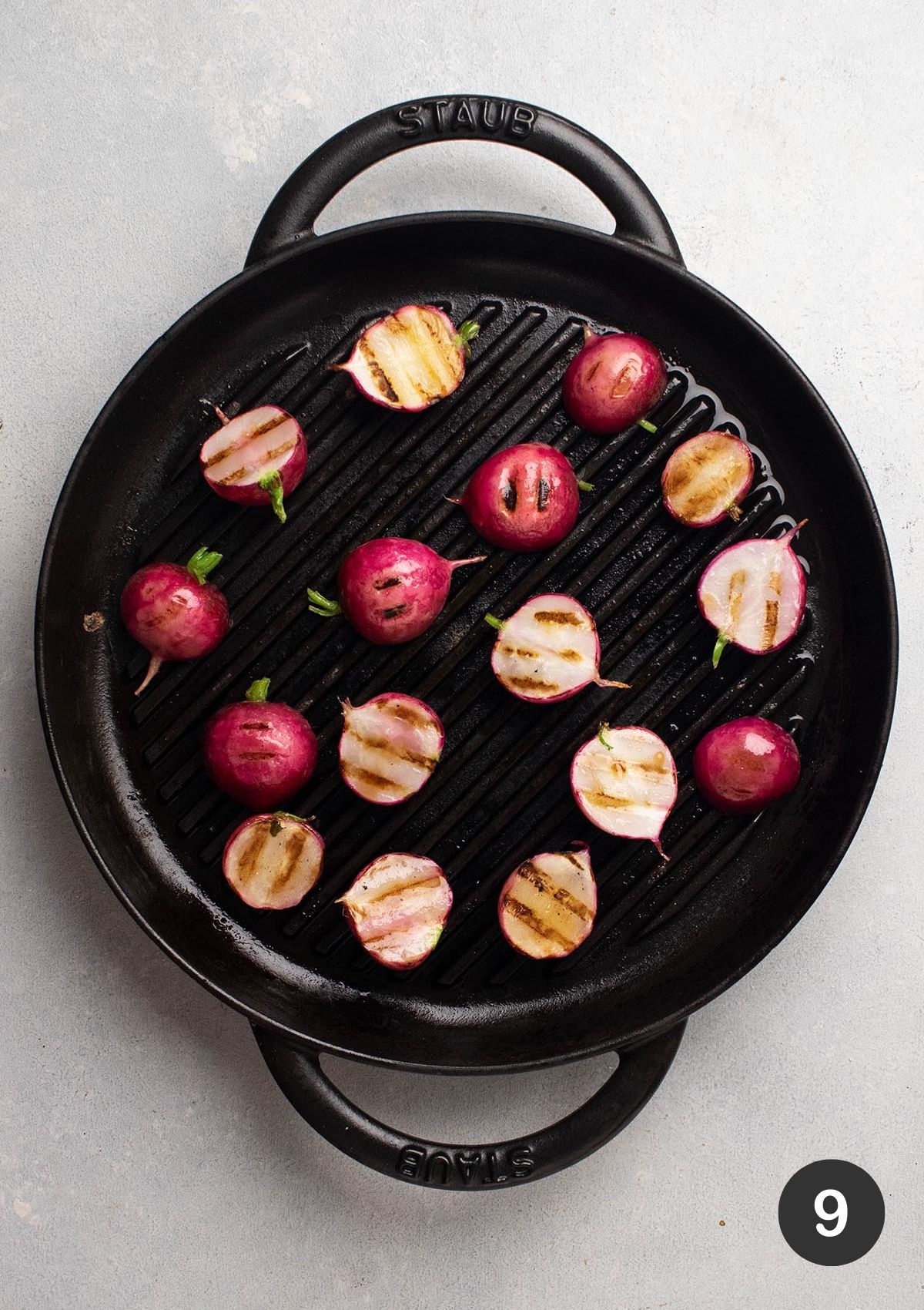 Cooking radishes on a black grill pan.