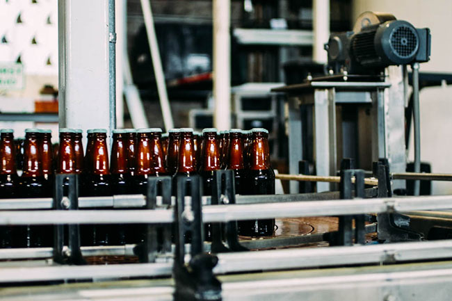 Brown beer bottles on a bottling assembly line.
