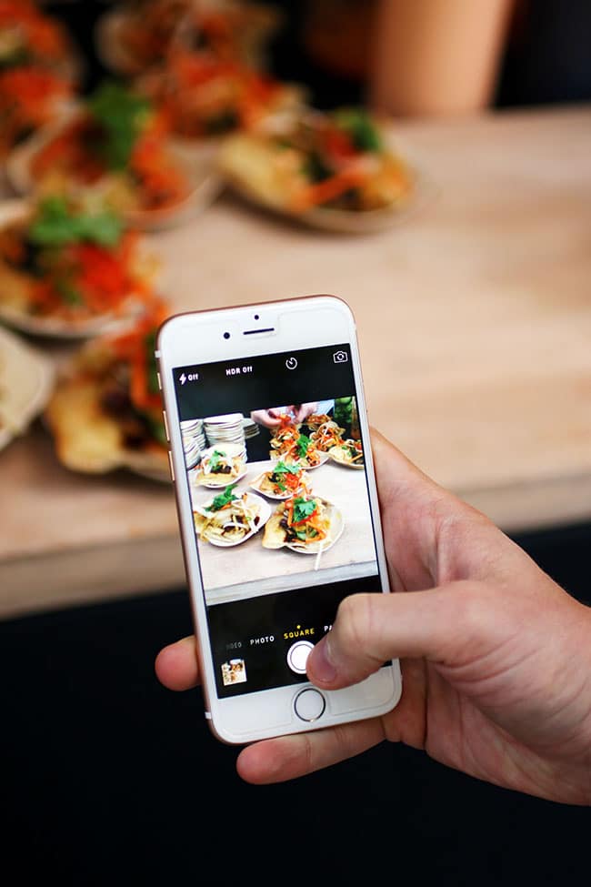 An iPhone taking a photo of a tostada appetizer.