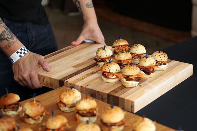 Large wooden cutting board filled with slider burgers.