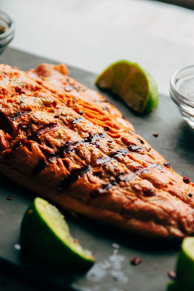 Grilled salmon fillet on a stone serving plate with lime wedges.
