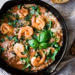 Baked shrimp in a cast iron skillet with tomatoes and basil.