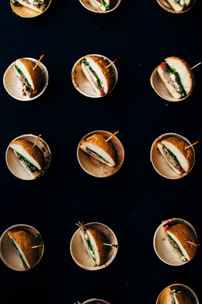 Half sandwiches in small wooden bowls on a black table.