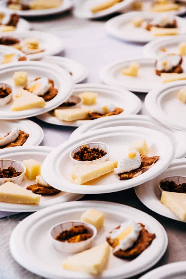 Appetizer plates filled with cheese samples stacked on a white table.
