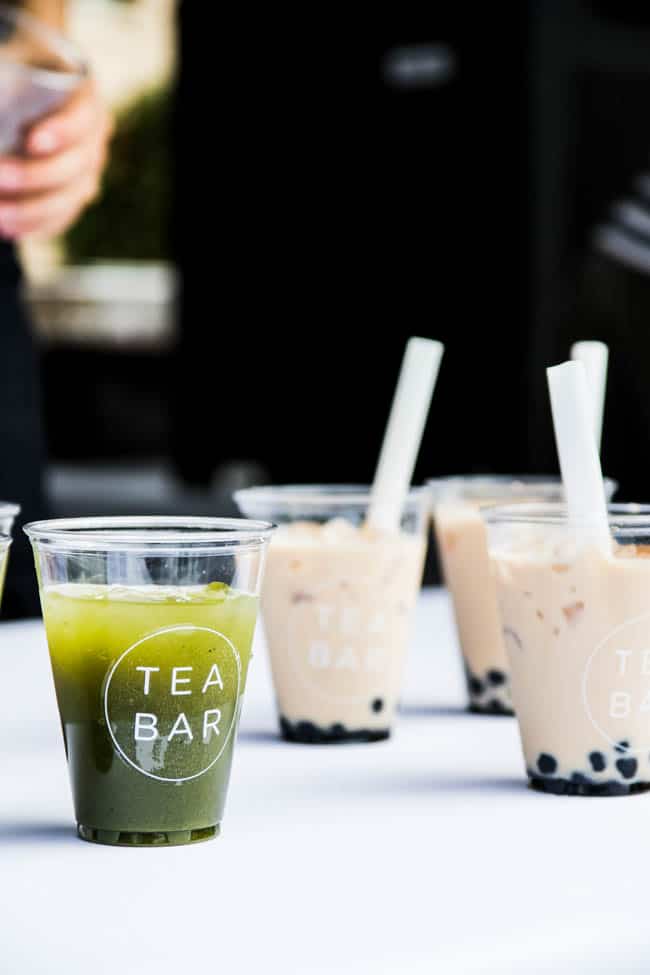 Several plastic cups of boba tea on a white table.