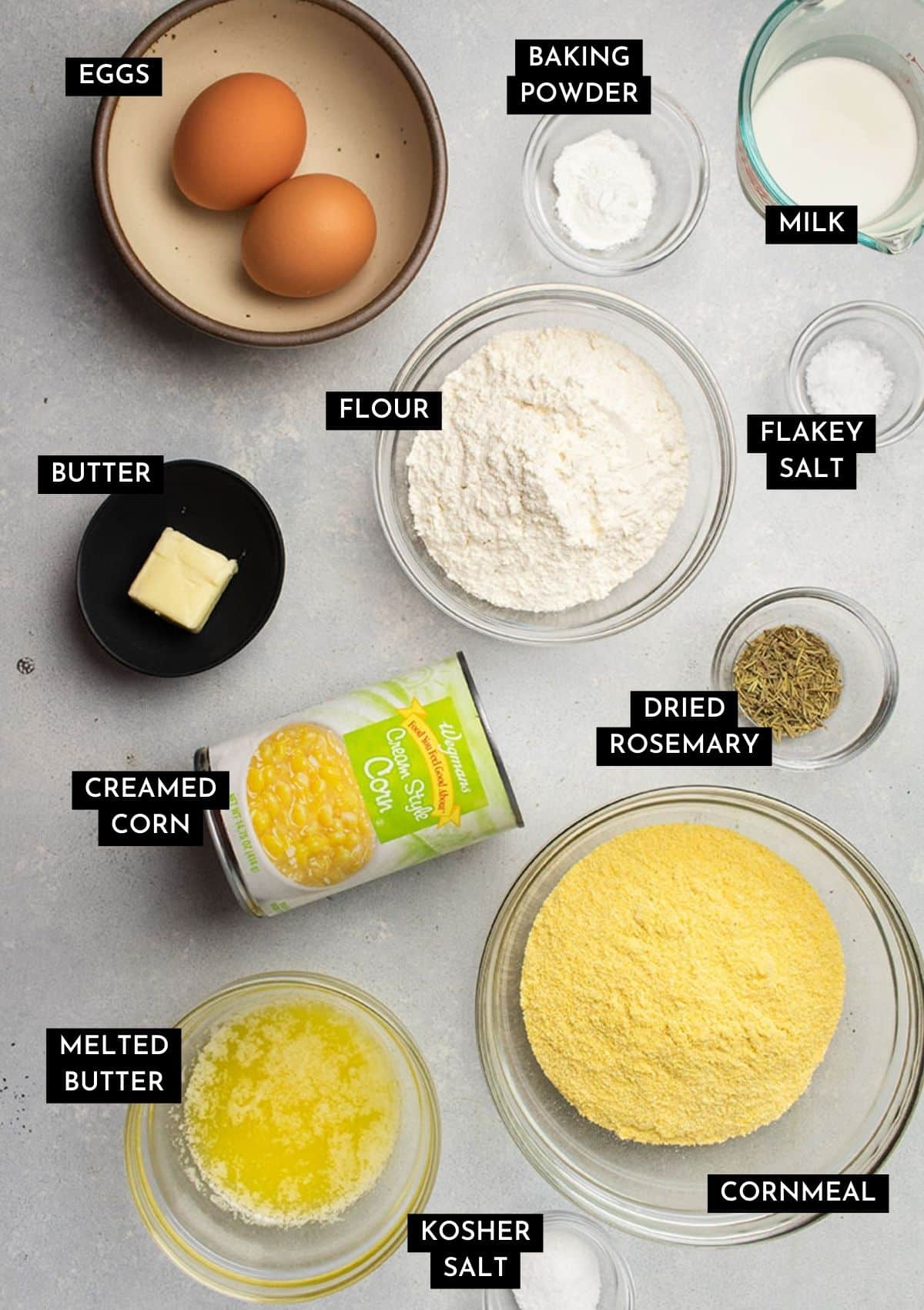 Cornbread ingredients, organized into individual serving bowls on a white table.