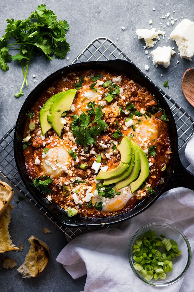 Overhead view of a cast iron skillet filled with baked eggs and tomato sauce.