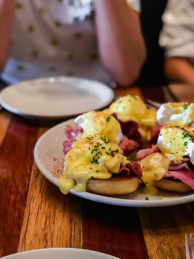 Platter of eggs benedict on a wood table.