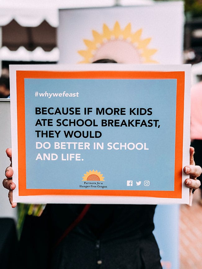 Hands holding a poster that says 'because if more kids ate school breakfast, they would do better in school and life.'