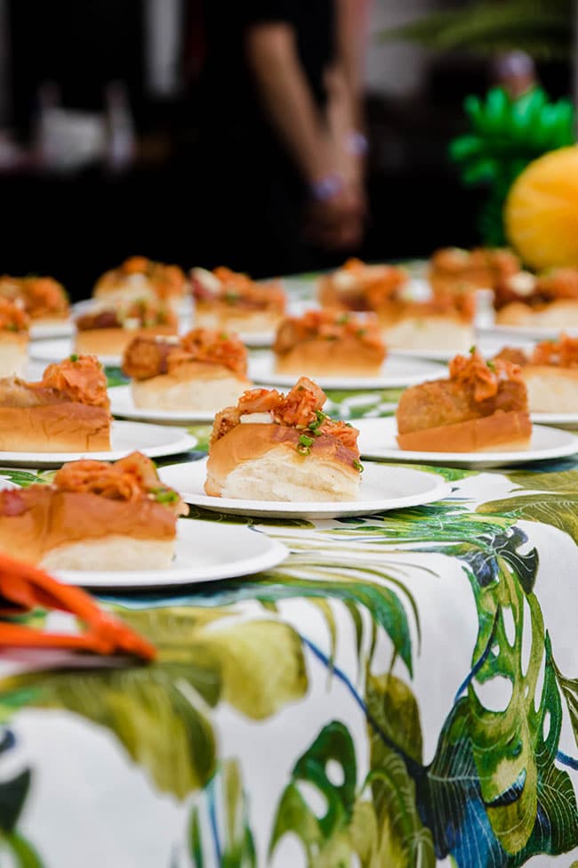 Lobster roll appetizers on individual plates on a floral print tablecloth.
