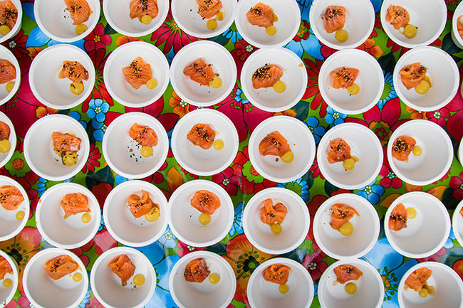 Dozens of small white bowls filled with pieces of sliced raw salmon.