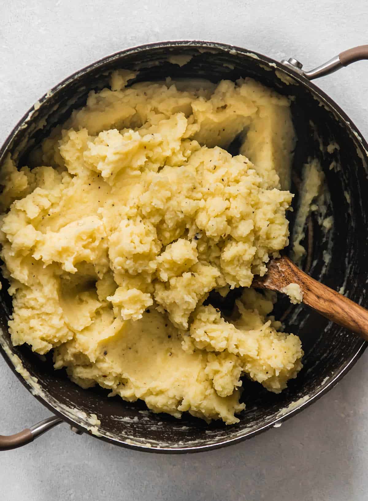 Stirring cauliflower mashed potatoes together in the pot.