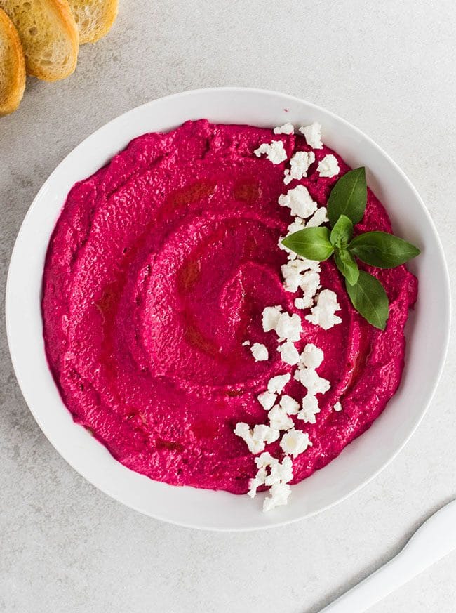 Beet dip in a shallow white bowl on a light grey table.