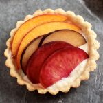 Small tart shell filled with sliced stone fruit.