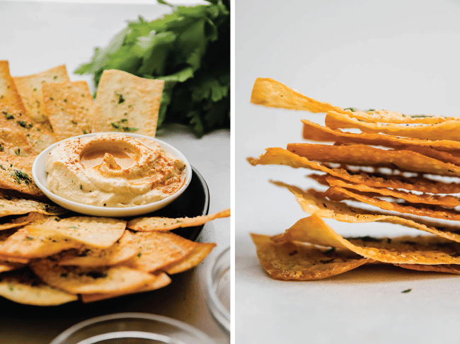 Thin wonton crackers on a black plate next to a bowl of hummus.