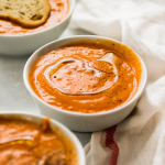Three small white bowls filled with creamy tomato soup.