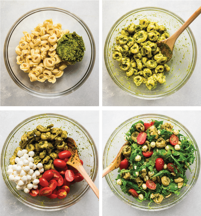 Wooden spoon mixing tortellini, pesto, mozzarella, and tomatoes together in a glass bowl.