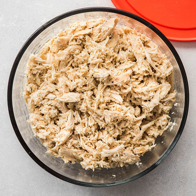 Glass dish filled with shredded chicken.