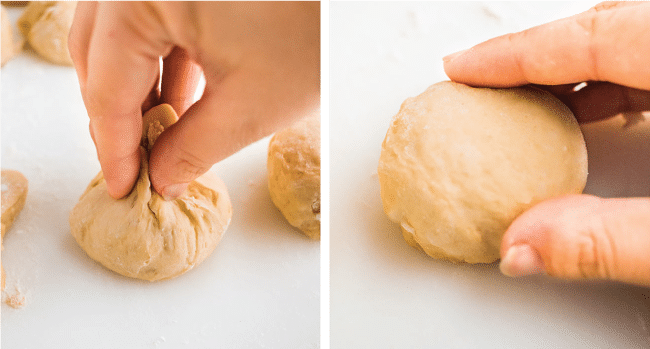 Woman\'s hands forming a small roll out of uncooked bread dough.
