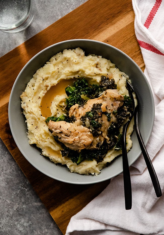 Mashed potatoes in a shallow blue bowl with chicken and kale.