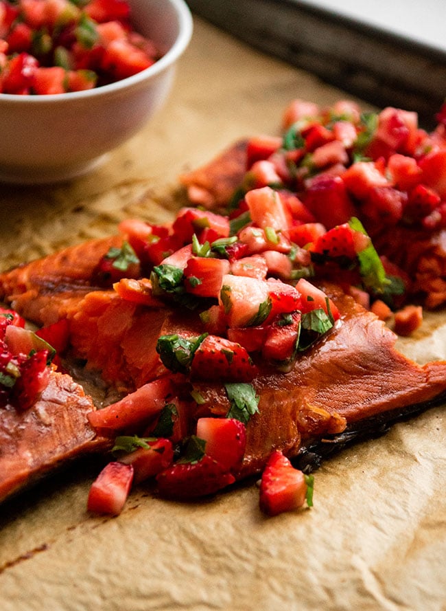 Salmon fillet topped with diced strawberries and cilantro.