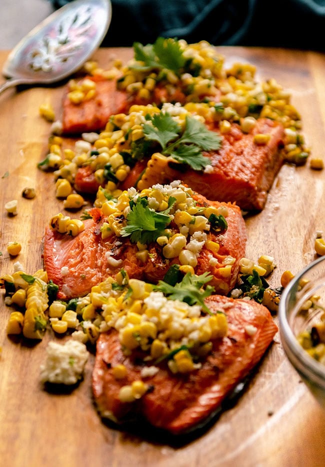 A fillet of grilled salmon, sliced into portions and topped with corn salsa.