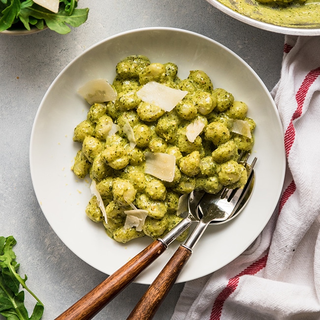 Gnocchi with pesto sauce in a shallow white bowl.