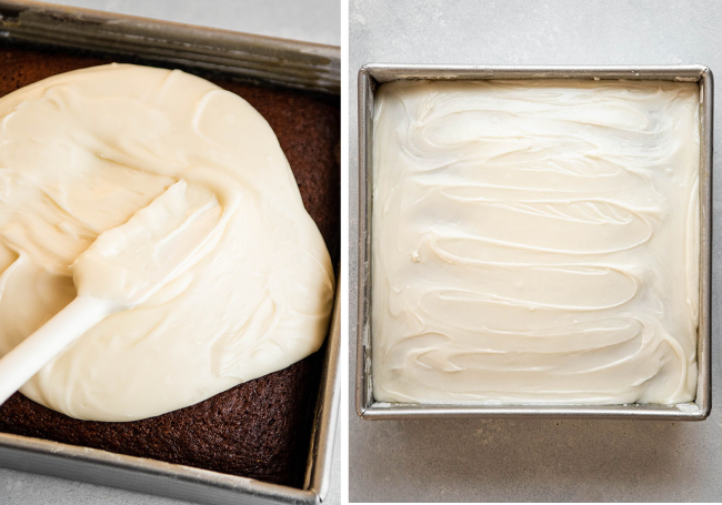White spatula spreading cream-colored frosting over a brown cake in a square cake pan.