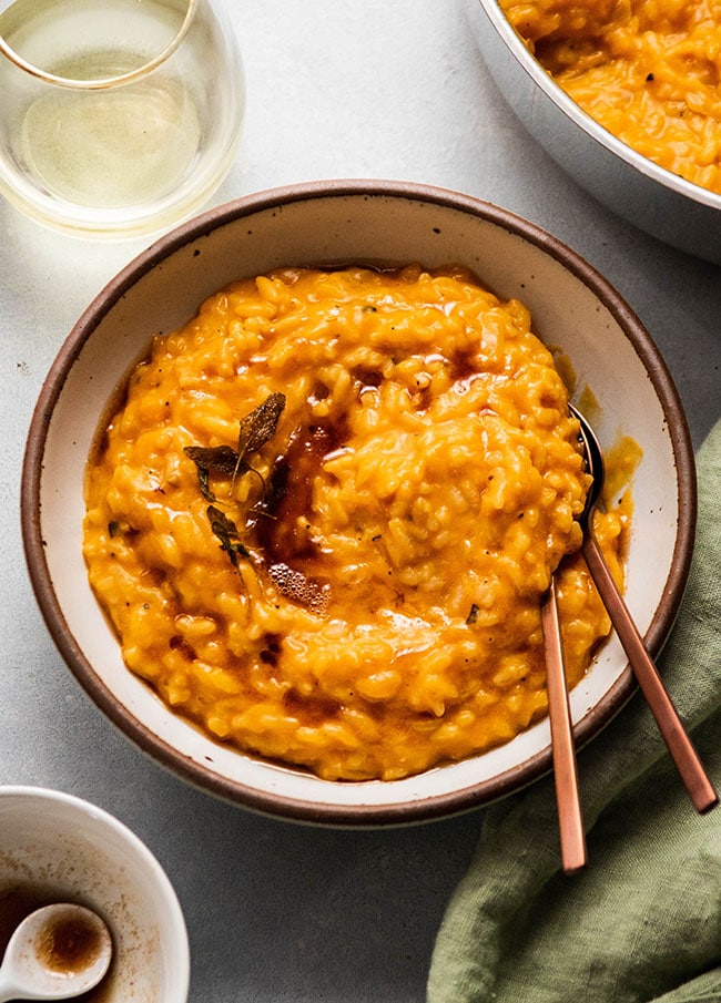 Butternut squash risotto topped with a drizzle of browned butter in a white ceramic bowl.