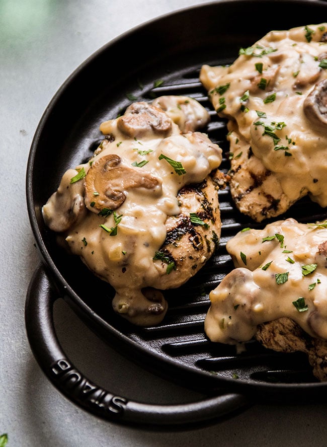 Grilled chicken breasts topped with mushrooms, cream sauce, and fresh parsley.