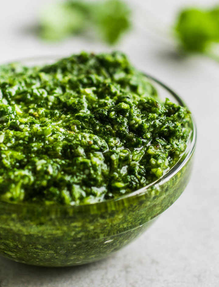 Close up of bright green pesto in a small glass bowl.