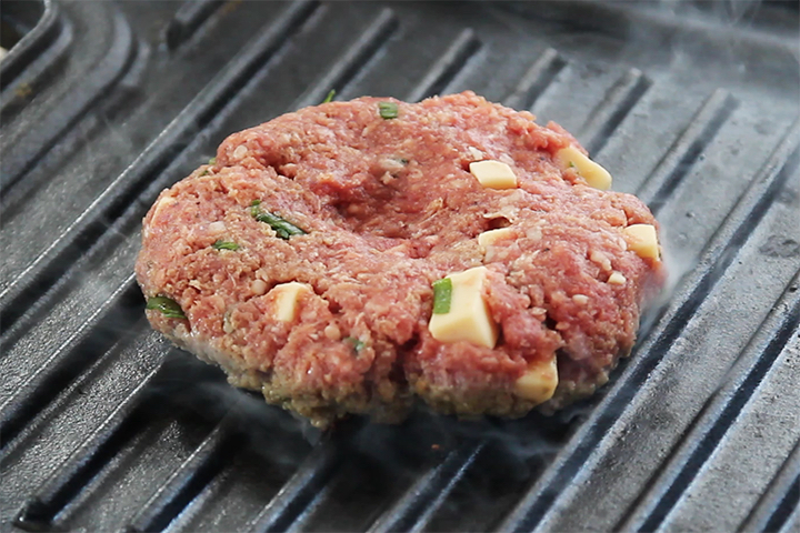 Burger patty on a black grill pan.