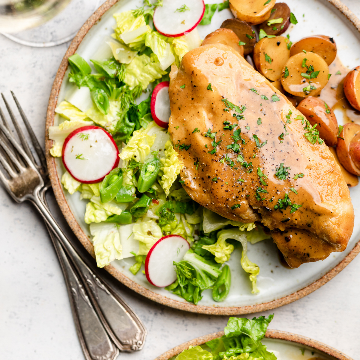 Maple dijon chicken on a plate with fresh salad and potatoes