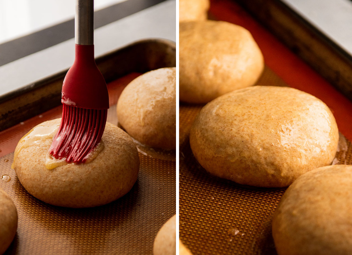 Red silicone pastry brush spreading melted butter over burger buns.