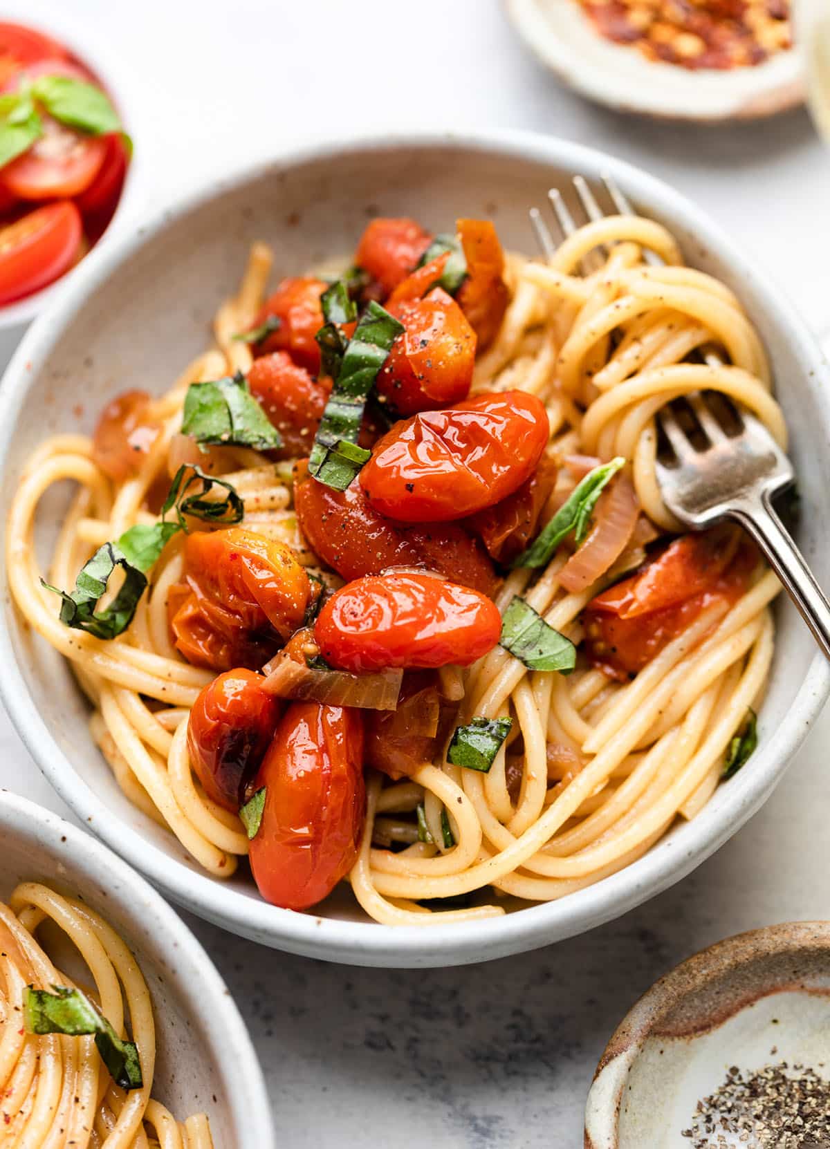 Spaghetti topped with burst tomatoes and fresh basil.