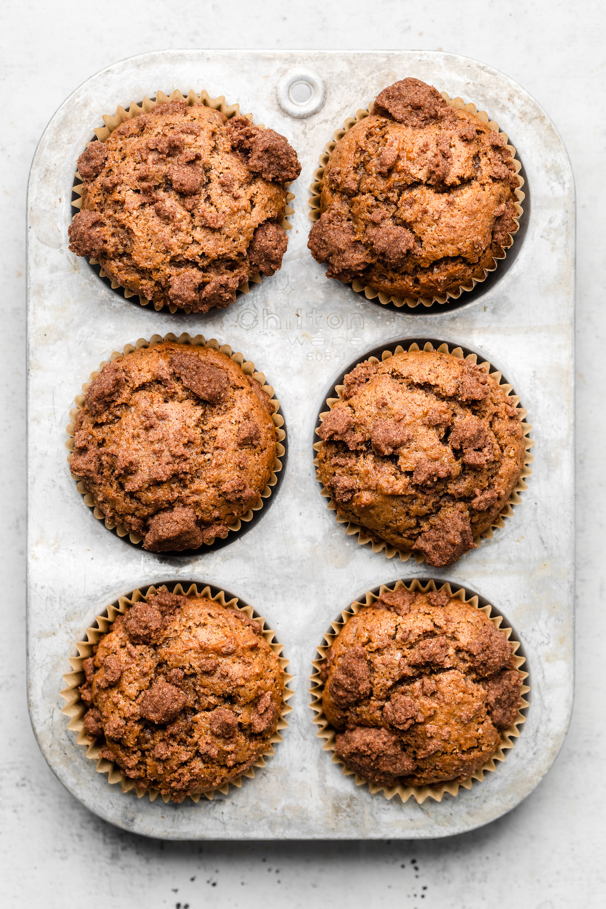Apple butter muffins in a silver muffin tin.