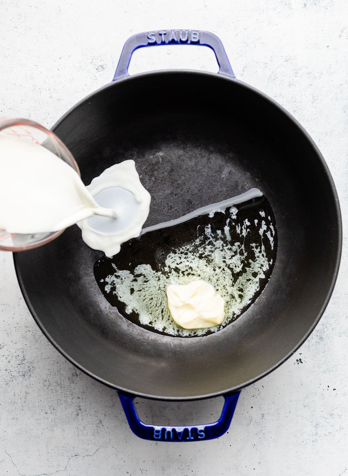 Pouring half and half into a large pot with melted butter.