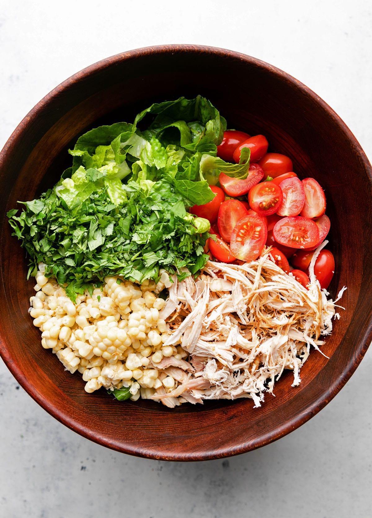Chicken chopped salad ingredients in a large brown bowl.